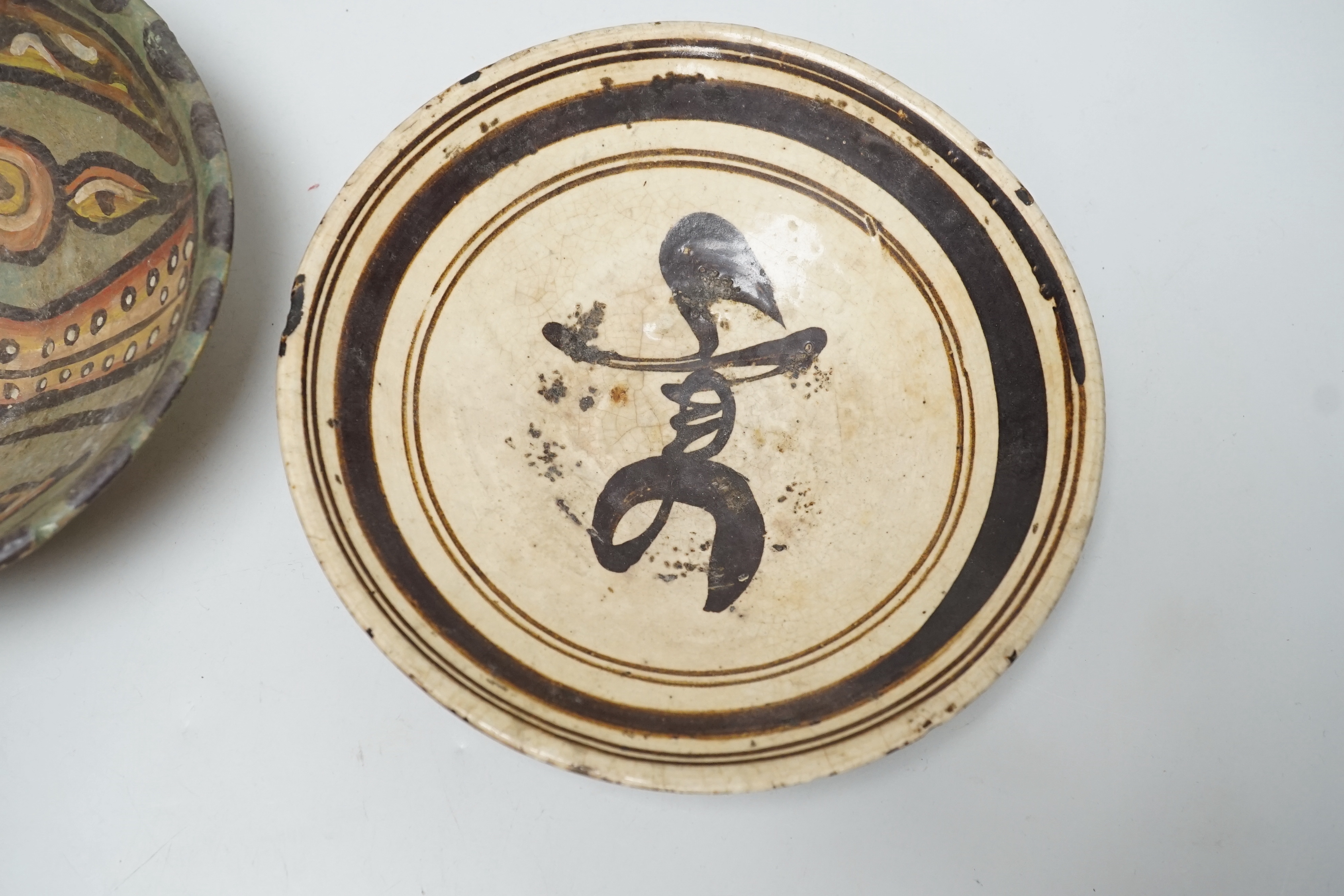 A 12th century Nishapur pottery bowl, painted with a bird, cracked and restored, together with a Chinese Cizhou pottery character dish, Yuan dynasty, largest 19cm diameter (2)